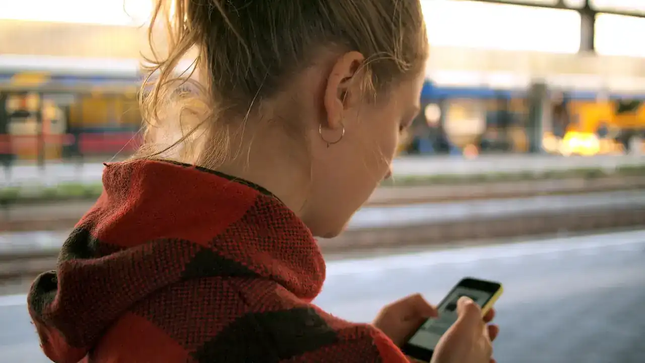 Una mujer mira su celular con atención.